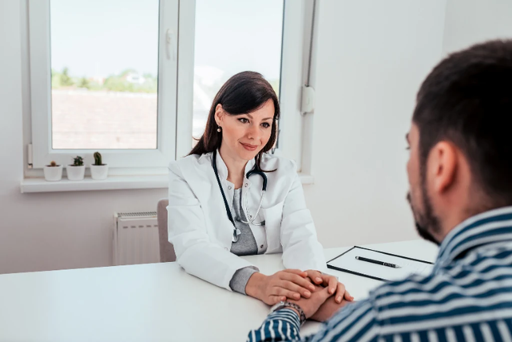 Médica conversando con un paciente durante una valoración en consultorio